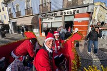 Pessoas vestidas de Pai Natal animam a rua junto à Cafetaria Bocage