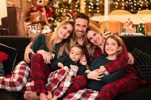 Família reunida em frente à árvore de Natal, com pijamas festivos