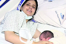 Mãe sorri com recém-nascido no hospital Such Roupa durante o Natal