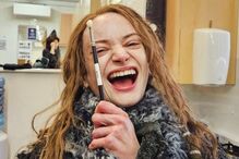 A atriz Anya Taylor-Joy sorri com uma escova de maquilhagem na mão