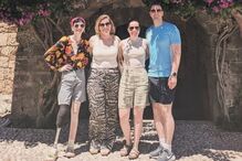 Grupo de pessoas posa para foto em frente a edifício histórico com flores roxas