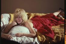 Brigitte Bardot relaxa numa cama com uma toalha vermelha