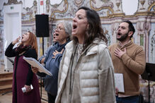 Um grupo de pessoas canta num coro, com partituras nas mãos