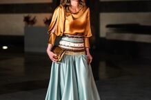 Rainha Rania da Jordânia com vestido dourado e azul durante evento oficial