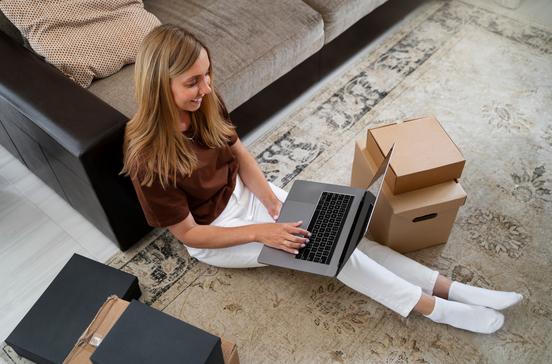 Mulher trabalha no computador portátil perto de caixas em promoção