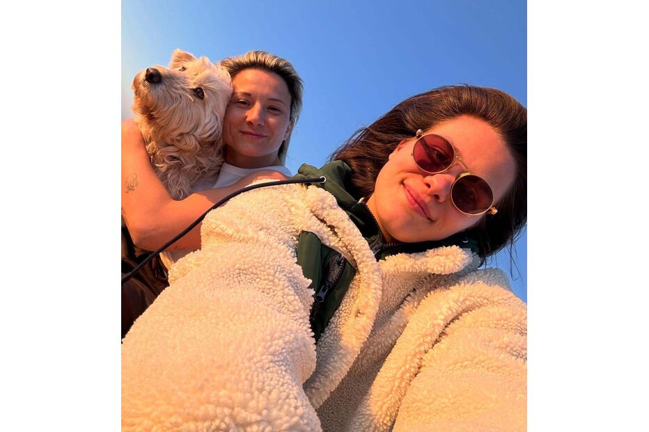 Selfie de duas pessoas e um cão com céu azul de fundo