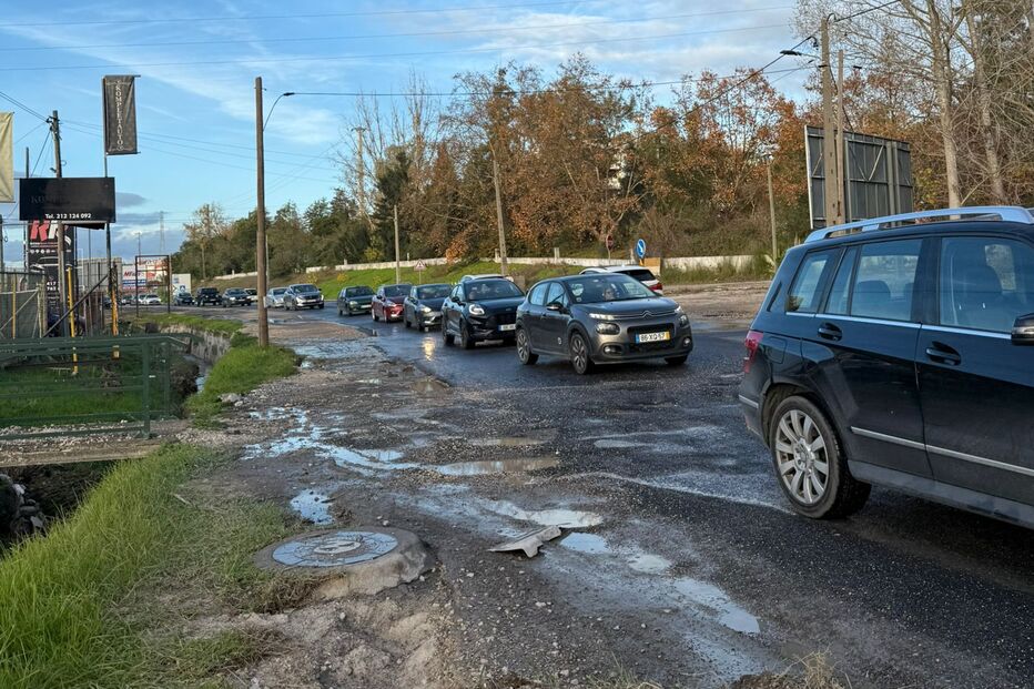 Trânsito lento numa estrada degradada com buracos e lama