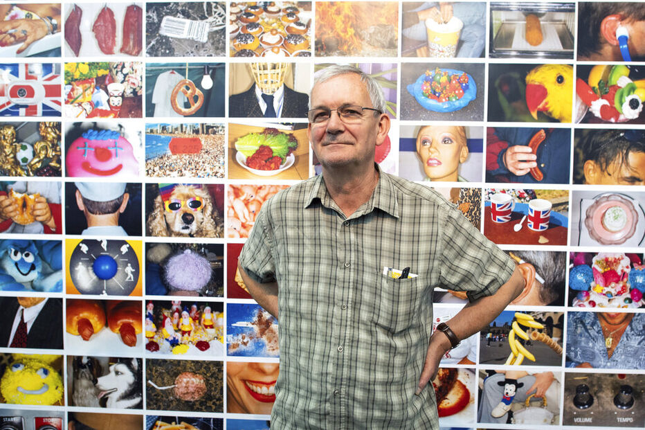 O fotógrafo Martin Parr posa em frente a um mural com as suas fotografias