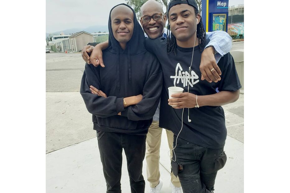 Três homens posam juntos para uma fotografia