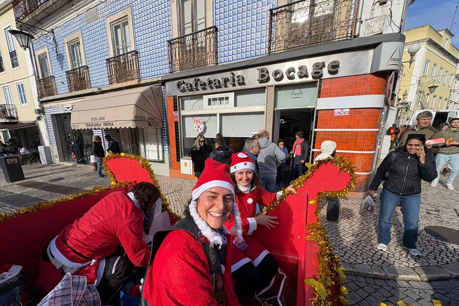 Pessoas vestidas de Pai Natal animam a rua junto à Cafetaria Bocage