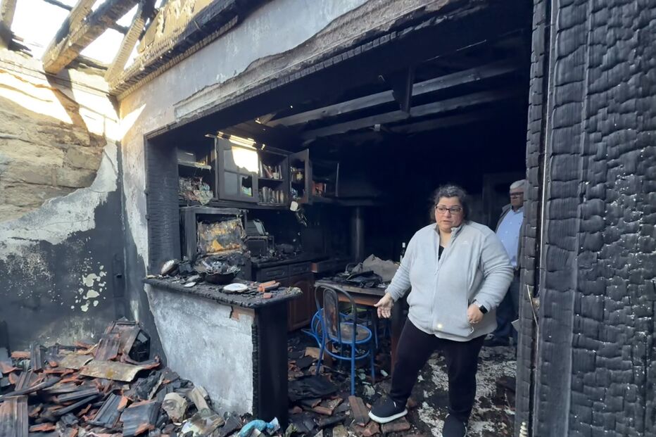 Mulher observa os estragos causados por um incêndio numa casa