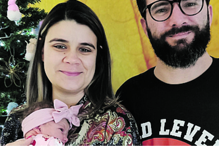 Bebé recém-nascido com família perto de uma árvore de Natal