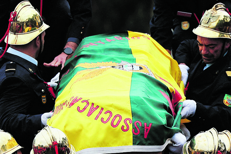 Bombeiros carregam caixão de colega falecido, coberto com a bandeira da associação
