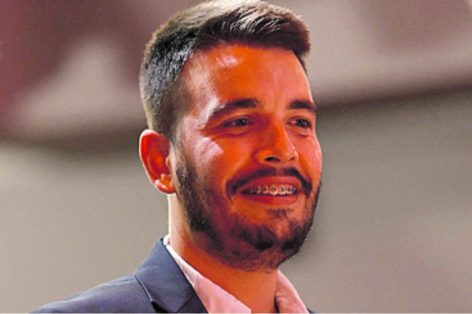 Retrato de homem sorrindo, com blazer azul e aparelho nos dentes