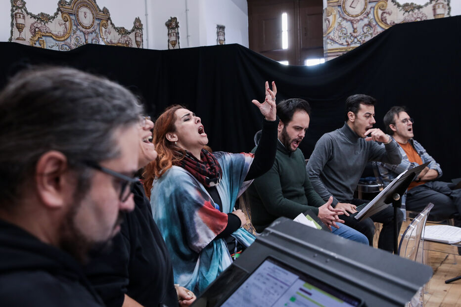 Grupo de pessoas canta num ensaio com partituras