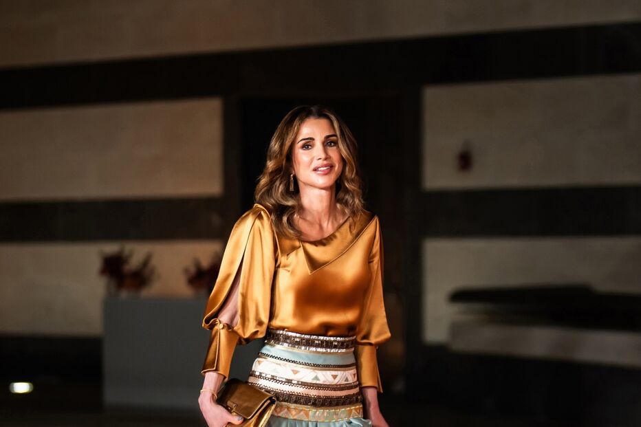 Rainha Rania da Jordânia com vestido dourado e azul durante evento oficial