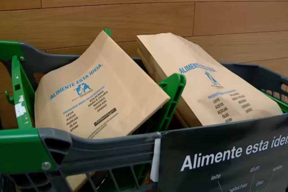 Cesto de compras com sacos de donativos para o banco alimentar