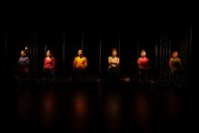 Reflexão sobre a imigração com pessoas sentadas em cadeiras no palco.
