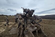 Militares operam sistema de artilharia em área aberta