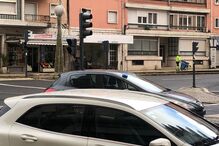 Rua em Lisboa com carros estacionados e funcionário da limpeza urbana