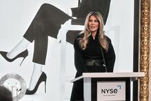Melania Trump discursa num evento com um cartaz promocional do documentário 'Melania'