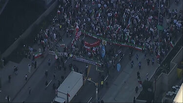 Multidão estende bandeira gigante do Irão durante manifestação em Los Angeles 