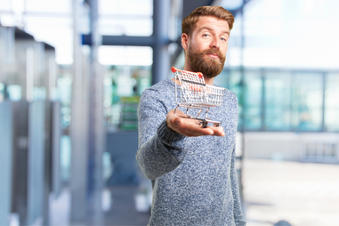 Homem segura carrinho de compras em miniatura