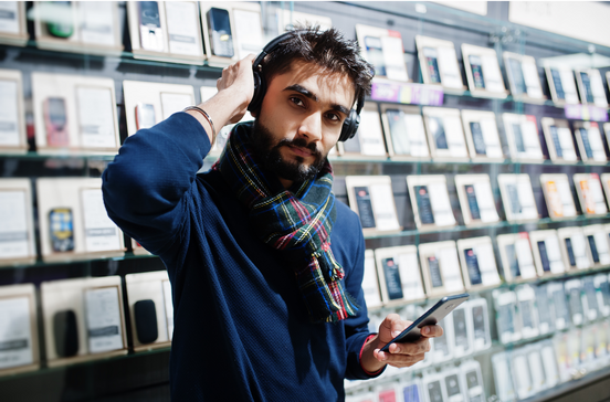 Homem barbudo com auscultadores e cachecol vê telemóvel