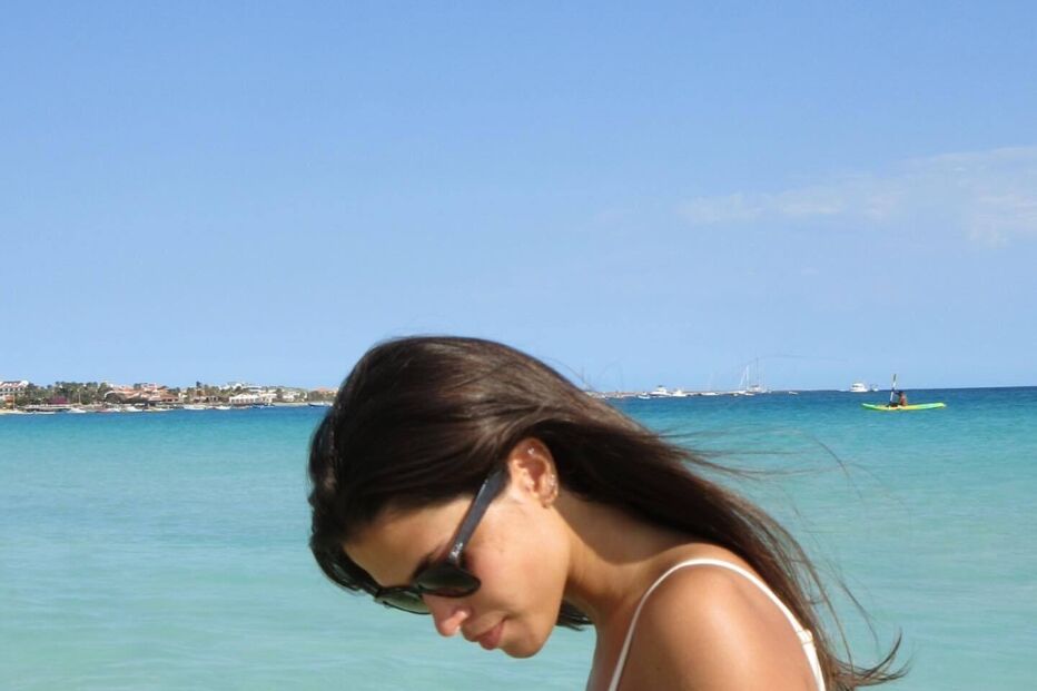 Mulher de fato de banho na praia com óculos de sol