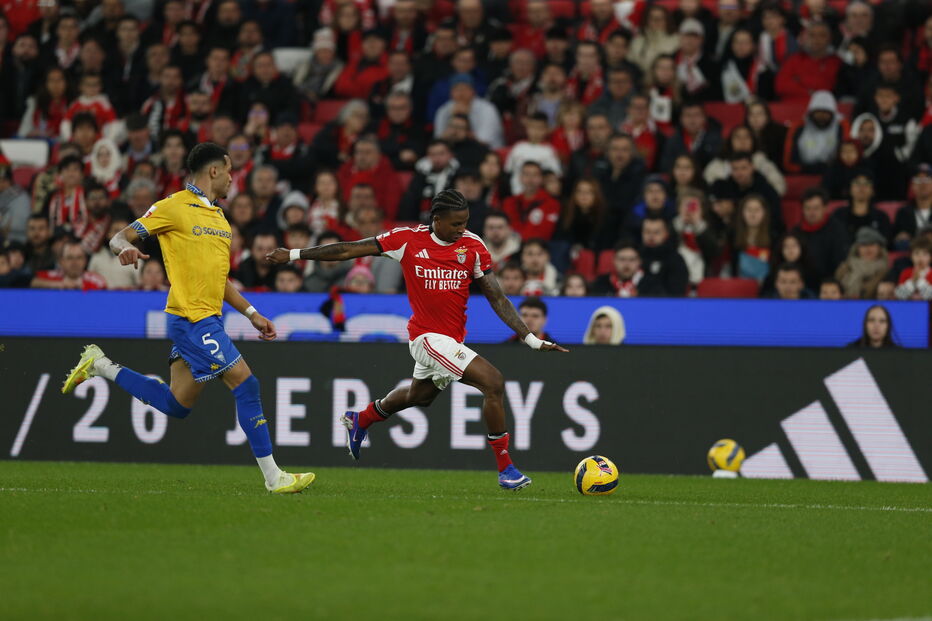 Jogador do Benfica domina a bola sob o olhar atento do defesa contrário