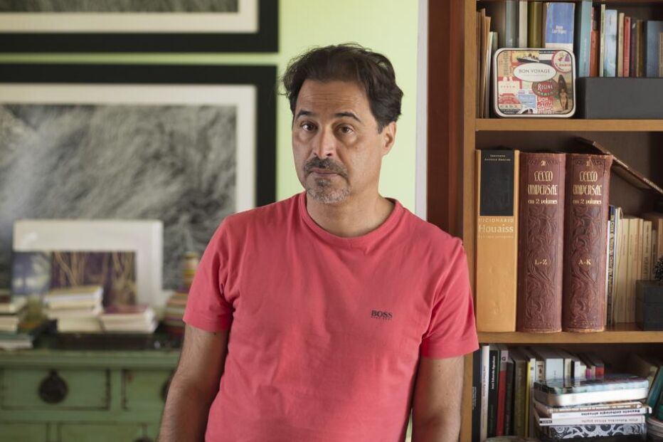 Retrato de homem junto a estante de livros e objetos