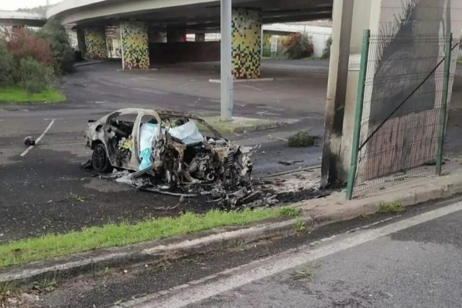 Um carro queimado estacionado junto a uma estrada