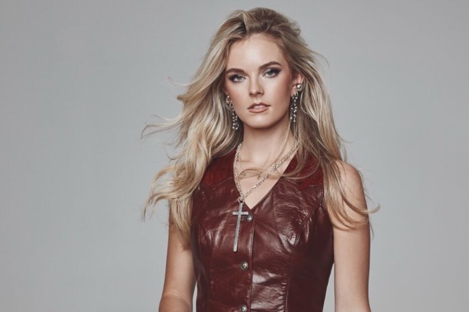 Mulher com colete de cabedal castanho e calças a combinar posa para a câmara