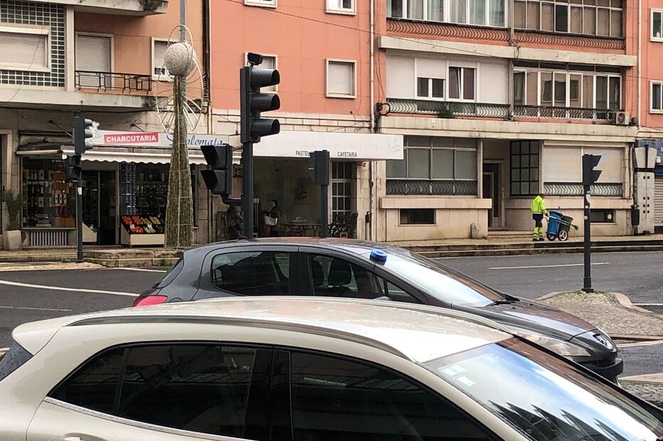 Rua em Lisboa com carros estacionados e funcionário da limpeza urbana