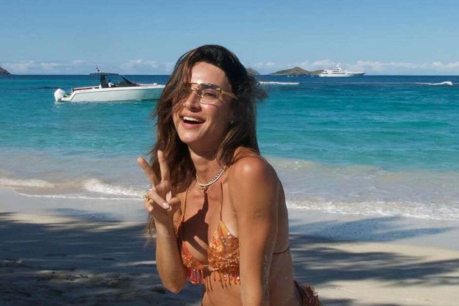 Mulher de biquíni na praia faz o sinal de paz