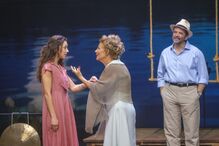 Atrizes contracenam num palco de teatro sob o olhar atento de um ator