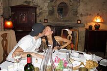 Casal partilha beijo romântico à mesa, num ambiente acolhedor