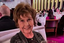 Mulher sorri com copo numa sala de jantar