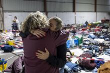 Duas mulheres abraçam-se e choram enquanto organizam bens doados para serem distribuídos pela população afetada pelas cheias, em Alcácer do Sal.