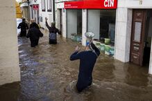Voluntários andam numa rua inundada à procura de pessoas que tenham ficado retidas na sua casa, na zona ribeirinha de Alcácer do Sal, Setúbal.