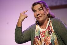 Mulher aponta para a cabeça num gesto pensativo durante apresentação