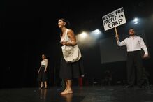 Atores em palco com cartaz a dizer 