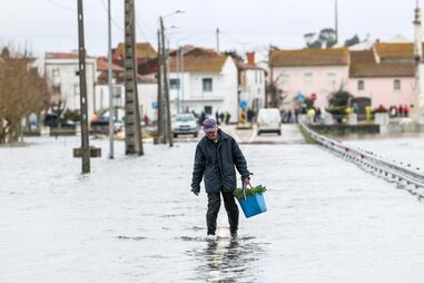Um popular atravessa uma estrada de acesso a Ereira, inundada devido à passagem da depressão Leonardo, Montemor-o-Velho