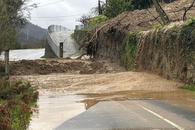 Estrada alagada e cheia de lama após deslizamento de terras