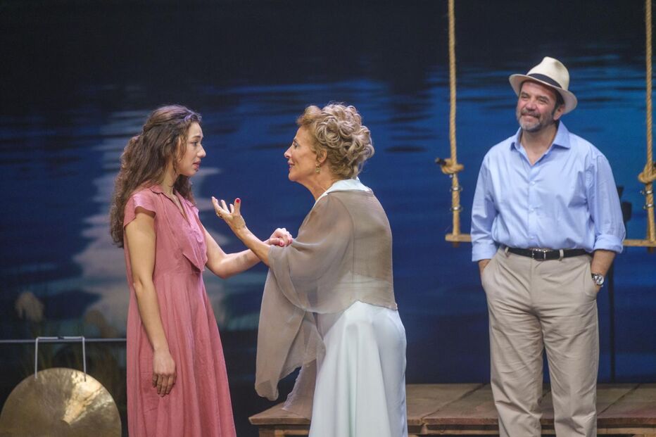 Atrizes contracenam num palco de teatro sob o olhar atento de um ator