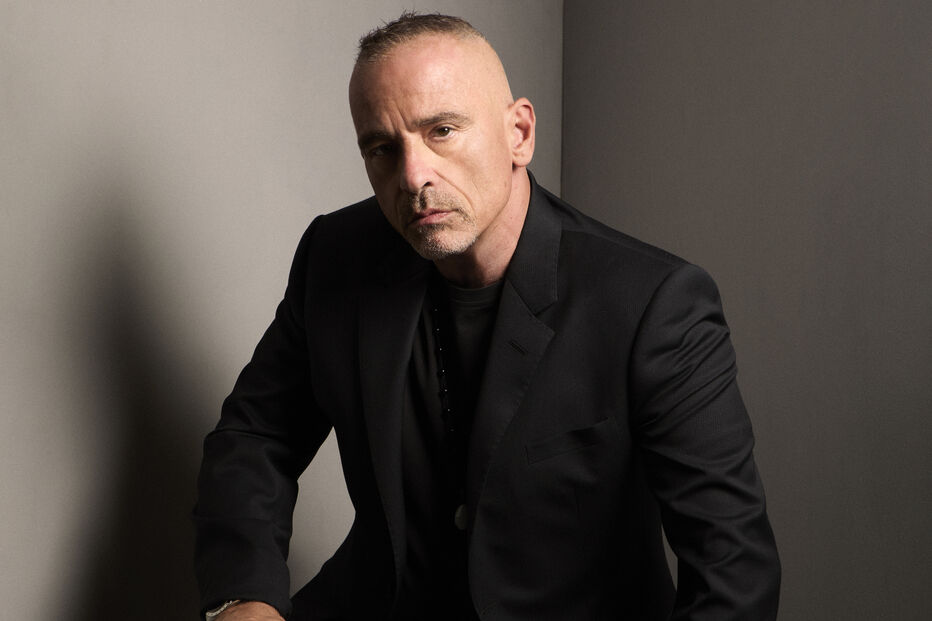 Eros Ramazzotti posa com um fato escuro num ambiente sóbrio