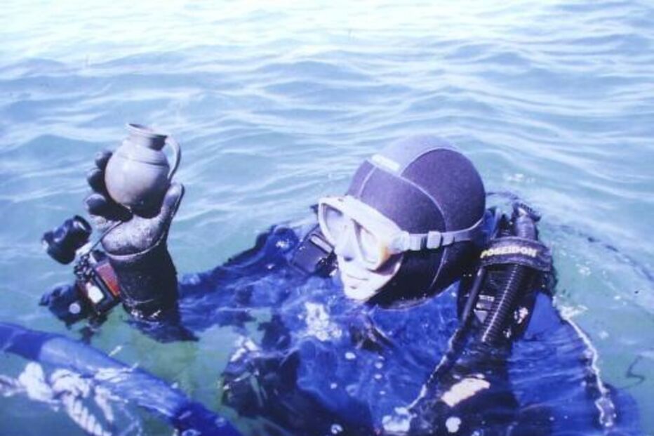 Mergulhador segura ânfora durante busca subaquática