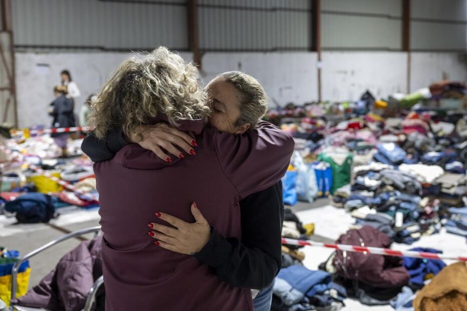 Duas mulheres abraçam-se e choram enquanto organizam bens doados para serem distribuídos pela população afetada pelas cheias, em Alcácer do Sal.