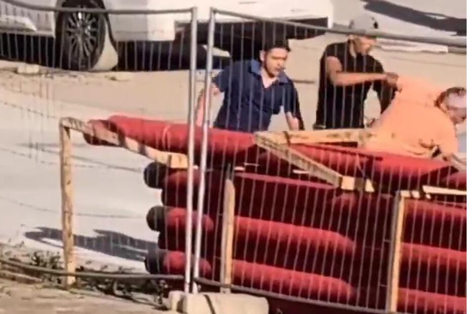 Homens ajudam pessoa a subir estrutura numa zona de construção