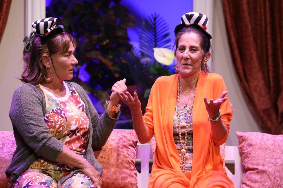 Atrizes em palco com figurino excêntrico e cores vibrantes